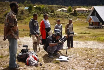 Small documentary film crew preparing a camera on an outdoor location
