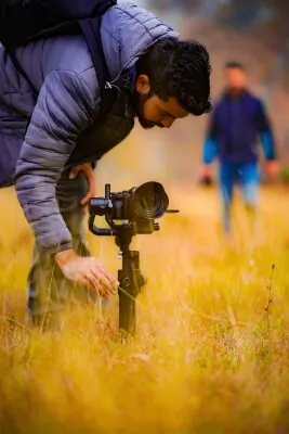 Camera operator adjusting a stabilised camera for an outdoor film shoot